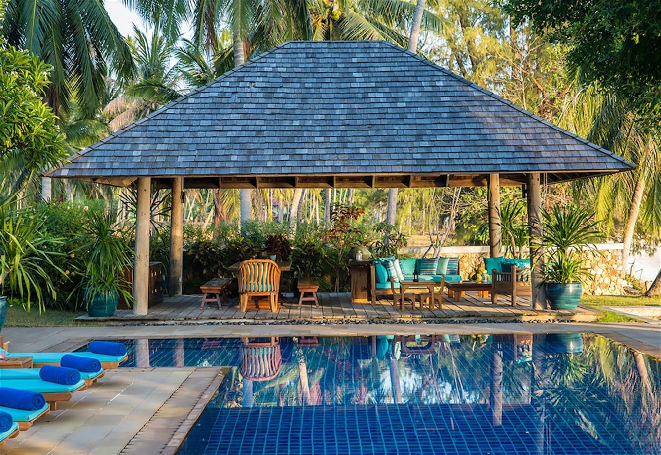 The infinity pool with a timber sala and sun loungers beside it
