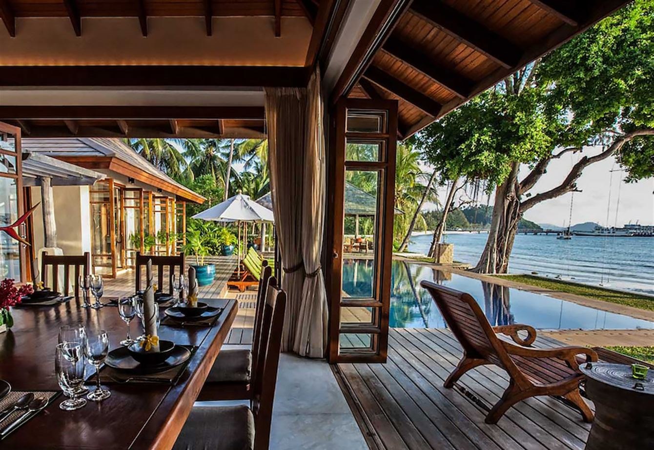 The long dining table set on the terrace, with the pool and the sea beyond
